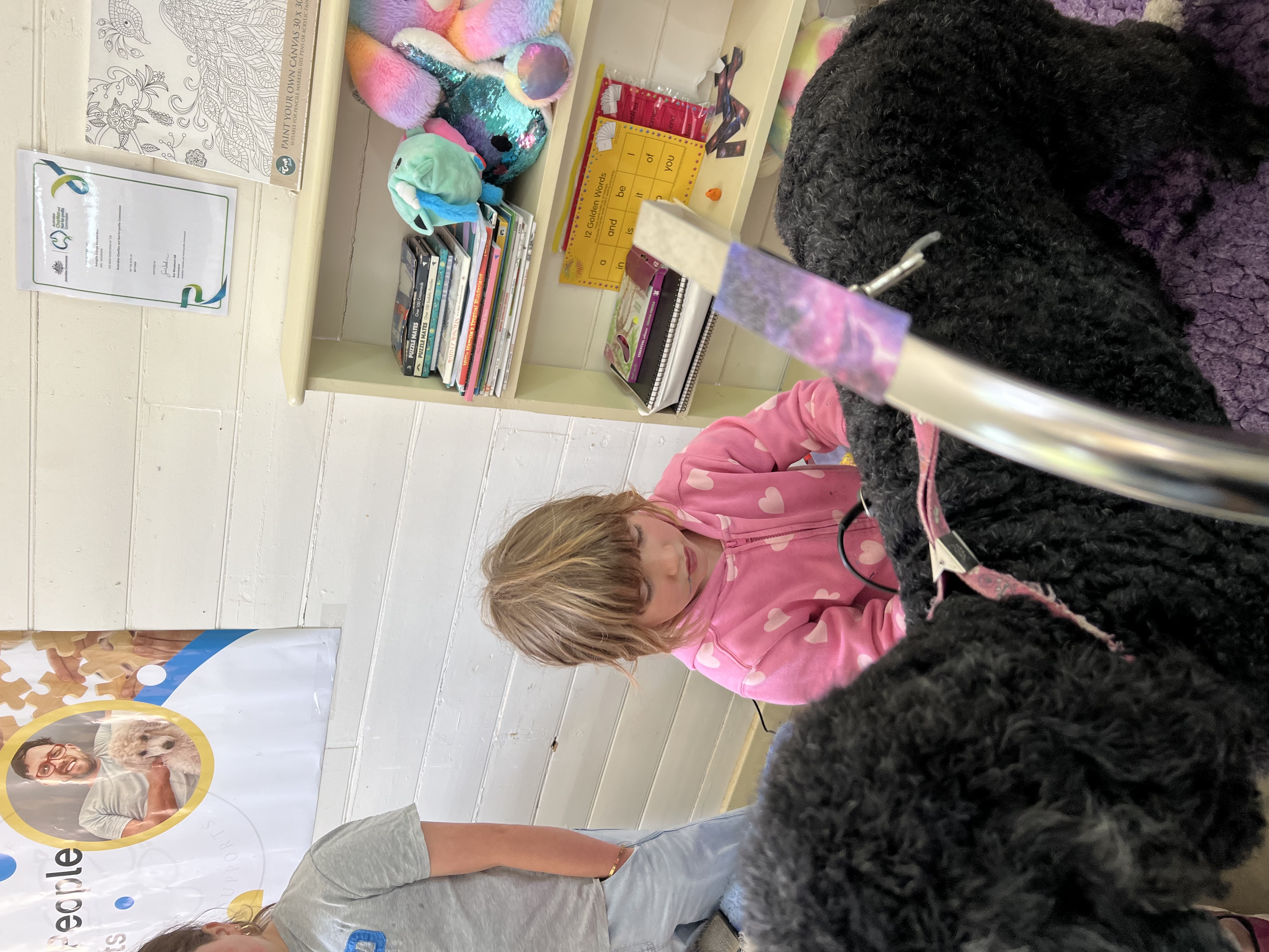 A child practising grooming with a black poodle during a holiday program
